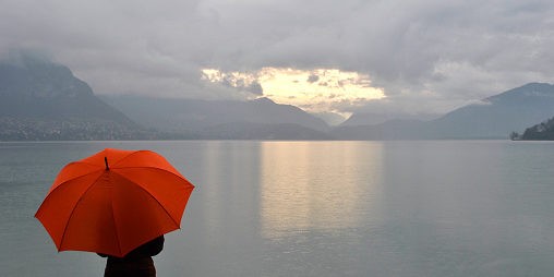 girl with umbrella meets sunrise on Lake Annecy in France